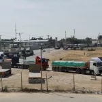 Trucks carrying aid wait to exit, on the Palestinian side of the border with Egypt, as the conflict between Israel and Palestinian Islamist group Hamas continues, in Rafah in the southern Gaza Strip on October 21, 2023 [Reuters/Ibraheem Abu Mustafa]