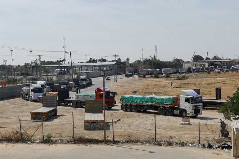 Trucks carrying aid wait to exit, on the Palestinian side of the border with Egypt, as the conflict between Israel and Palestinian Islamist group Hamas continues, in Rafah in the southern Gaza Strip on October 21, 2023 [Reuters/Ibraheem Abu Mustafa]